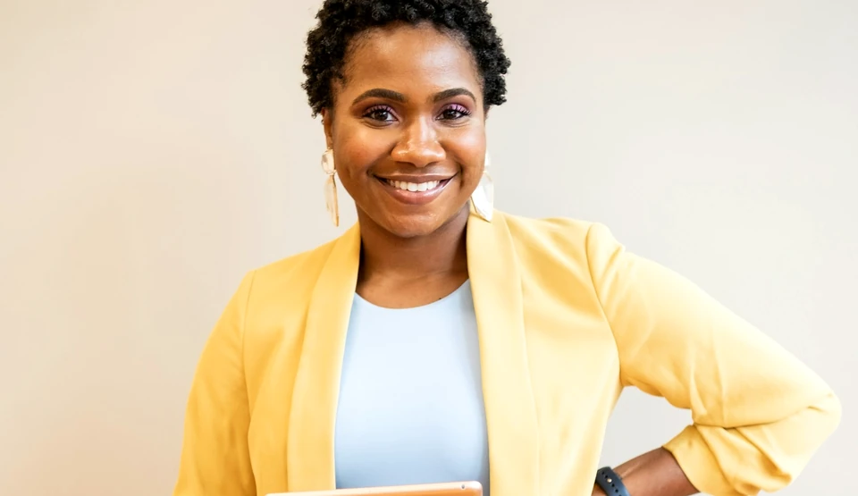 Black technology professional smiling in a studio portrait; photograph by Alex Starnes via Unsplash
