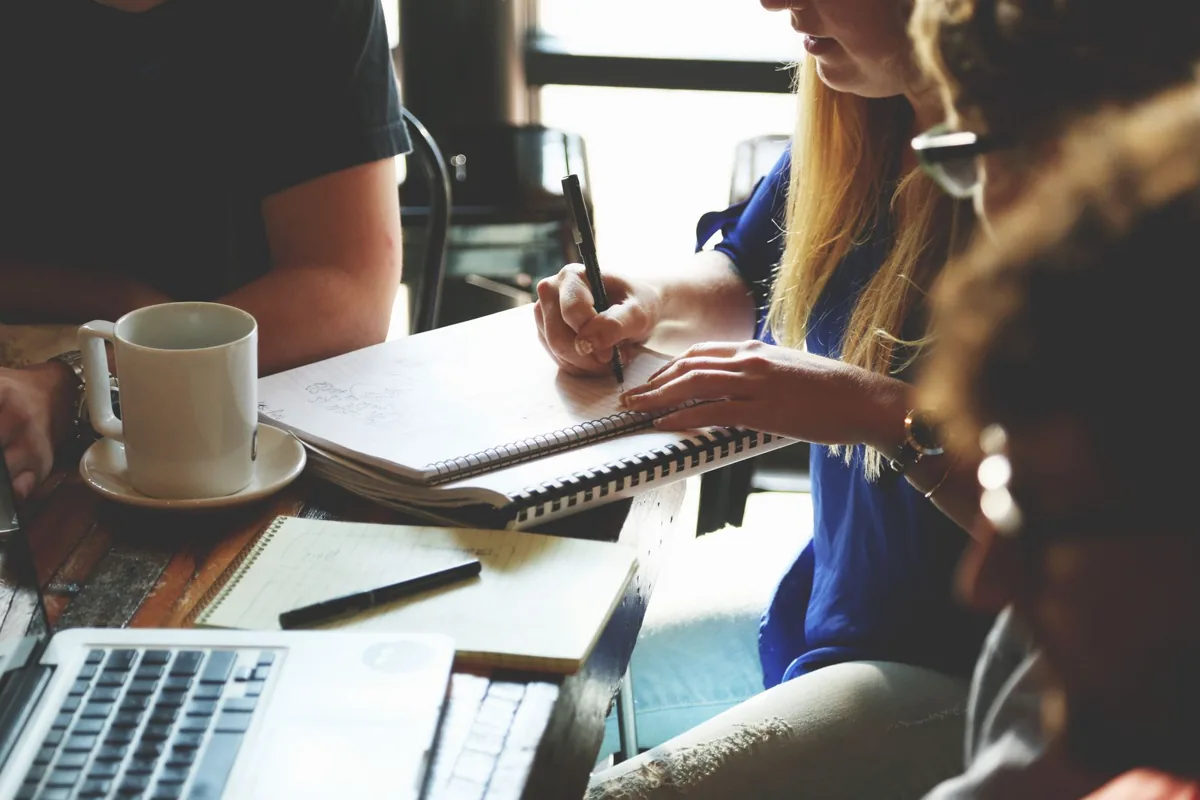 Colleagues taking notes beside a laptop; illustrative customer-relationship planning photograph