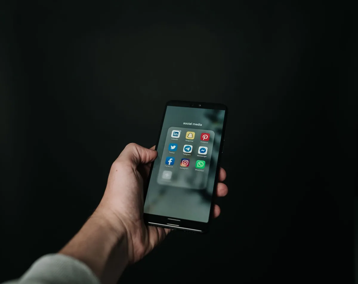 Hand holding a smartphone with communication apps; illustrative photograph, not a product interface
